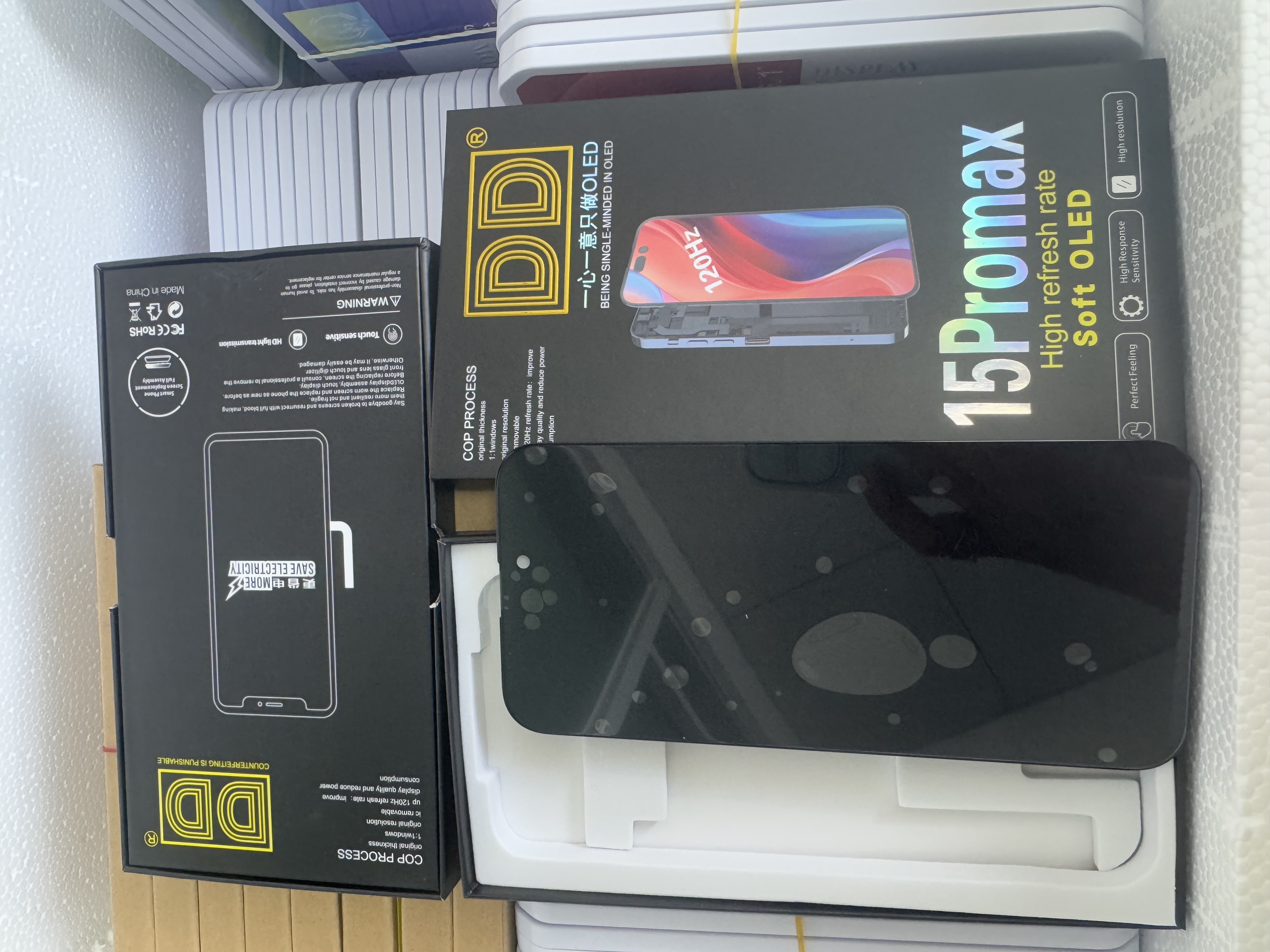 OLED phone screen assembly for iPhone 15 Pro Max showing front display with punch-hole camera cutout and earpiece grille.