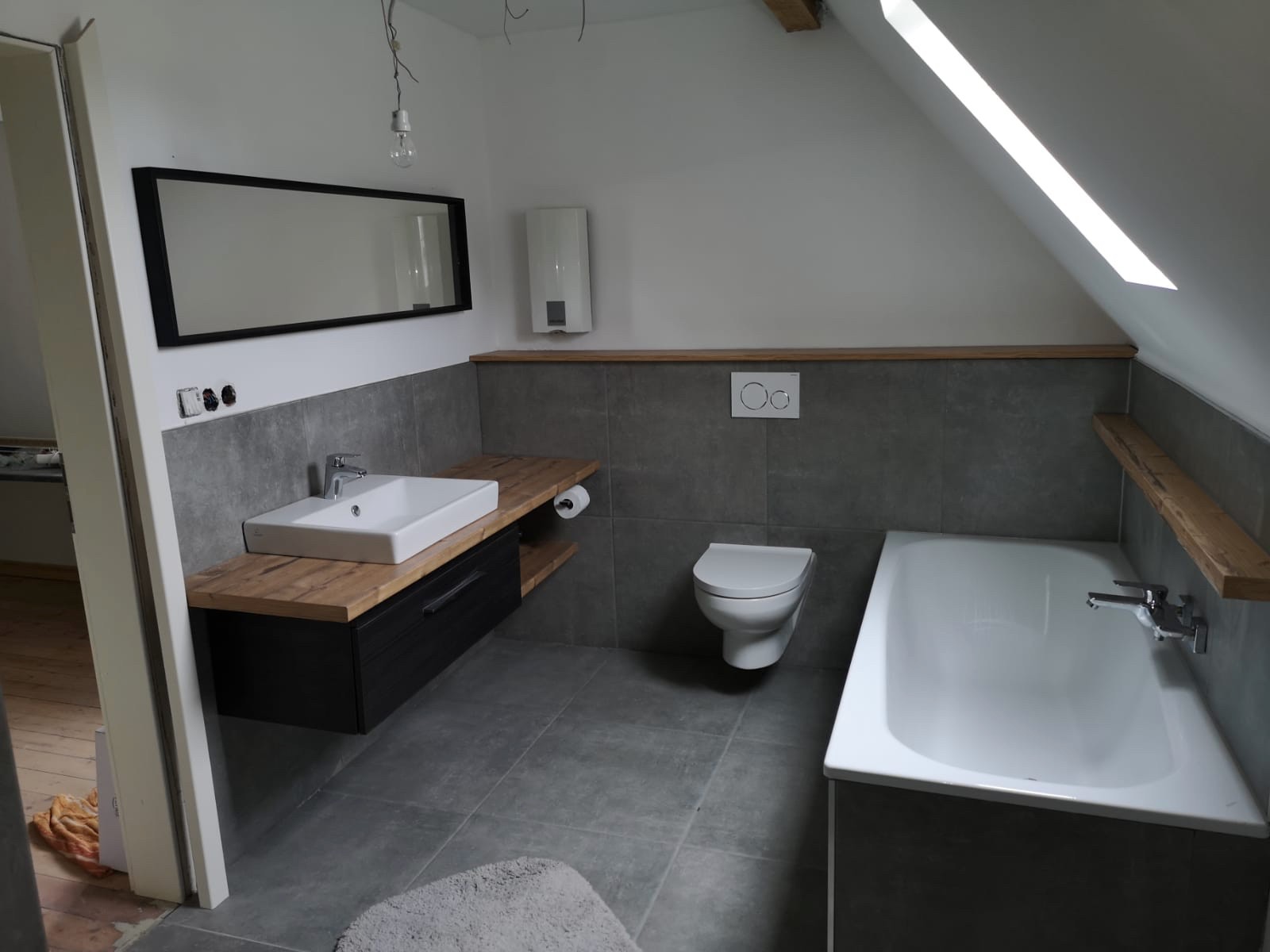 Nyt moderne badeværelse efter renovering – antracitgrå fliser og egetræsmøbel