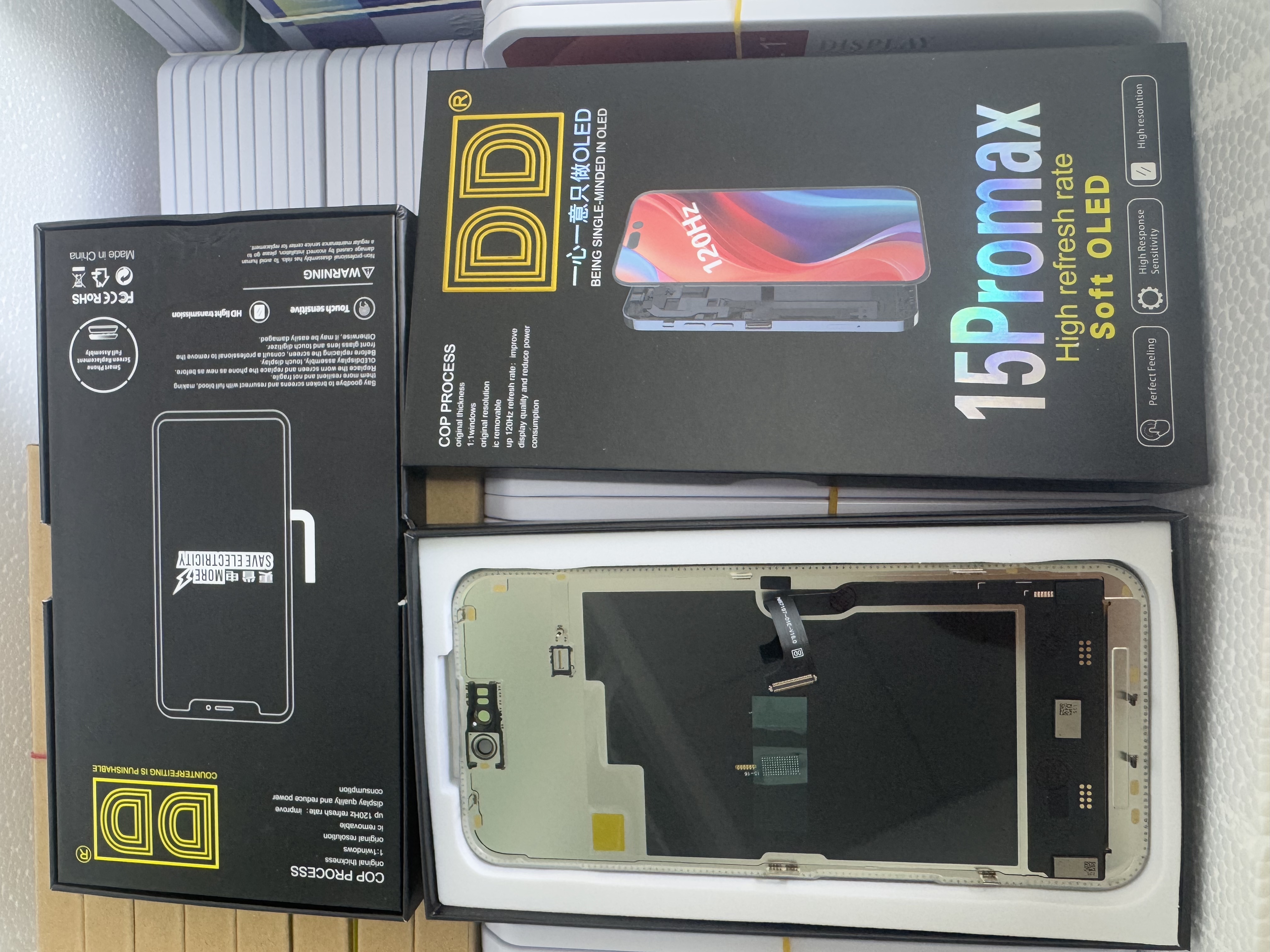 OLED screen assembly back view showing flexible printed circuit cable, driver IC chip, and protective tape for iPhone 15 Pro Max.