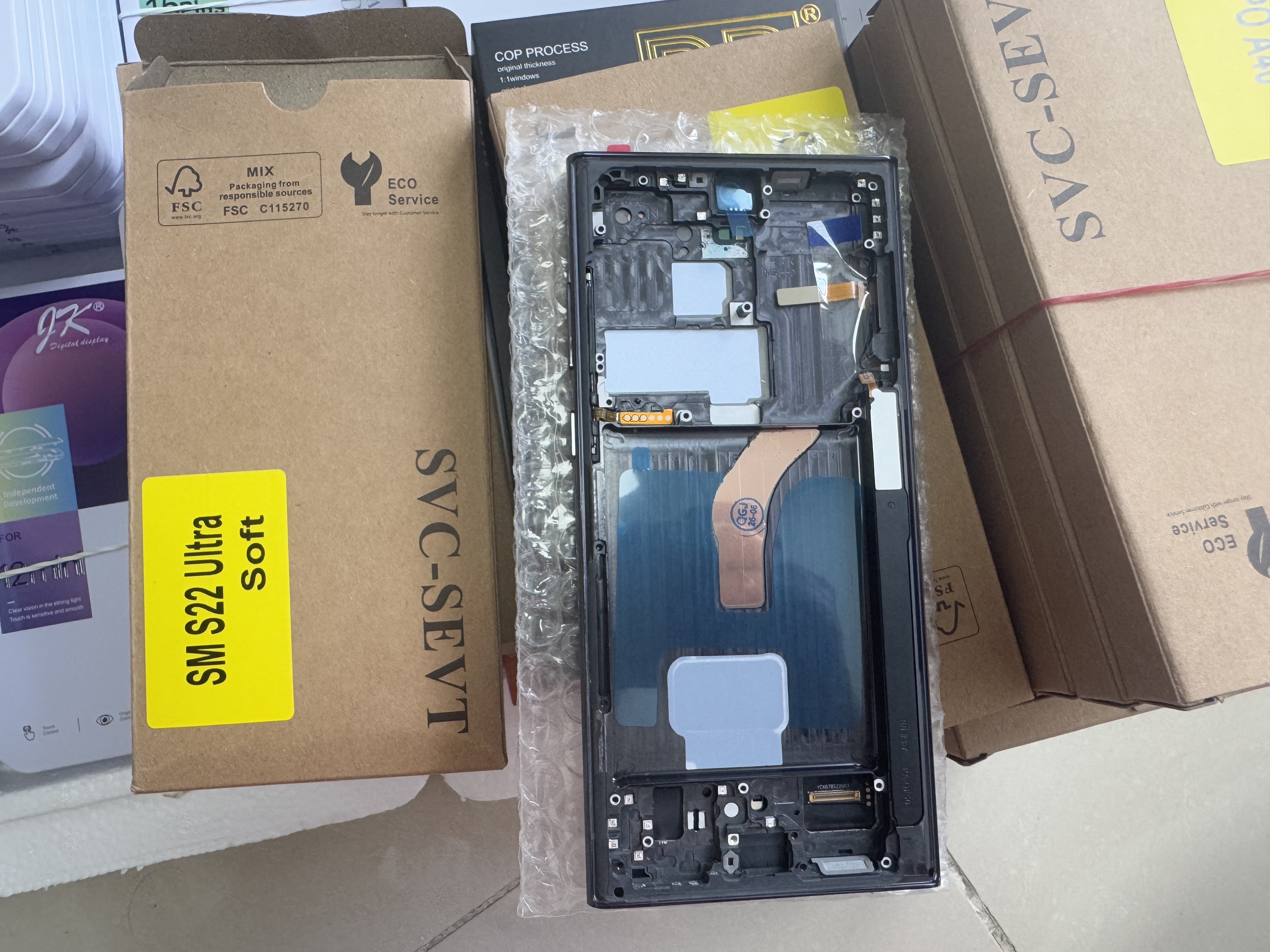 Samsung Galaxy S22 Ultra screen assembly with metal frame, flex cables and yellow identification label showing SM S22 Ultra Soft model number.